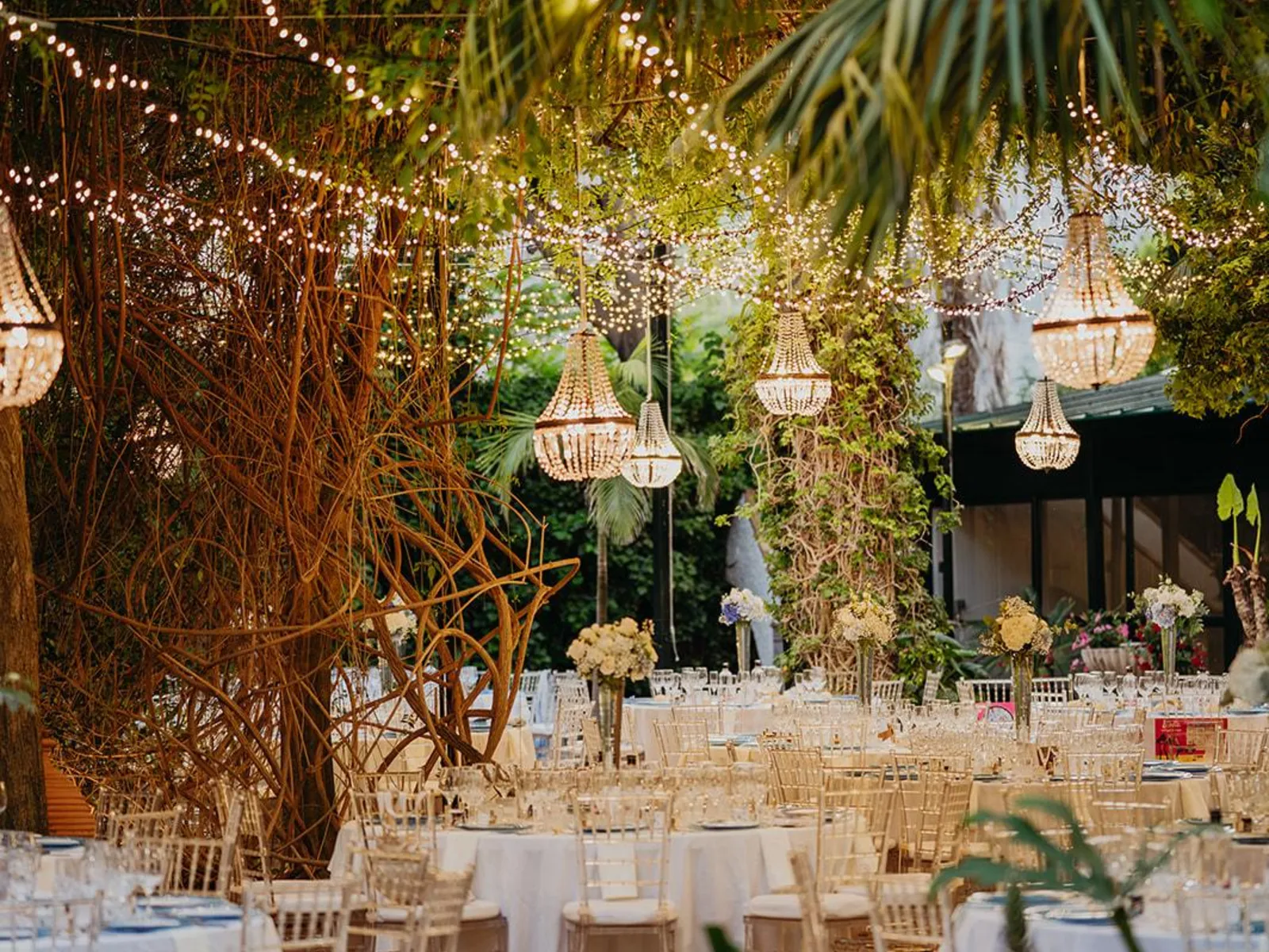Banquete de boda bajo luces y lámparas de araña en un jardín de Málaga