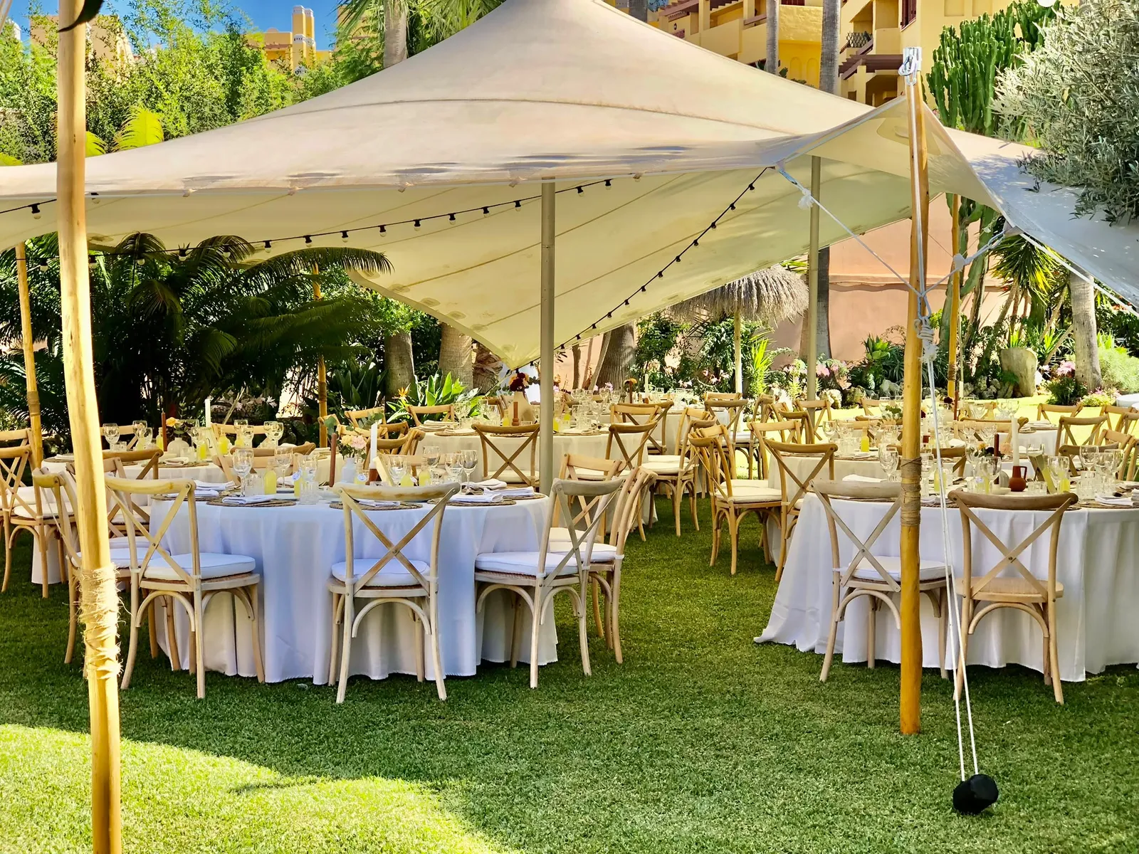 Banquete en carpa con mesas redondas en un jardín de la Costa del Sol