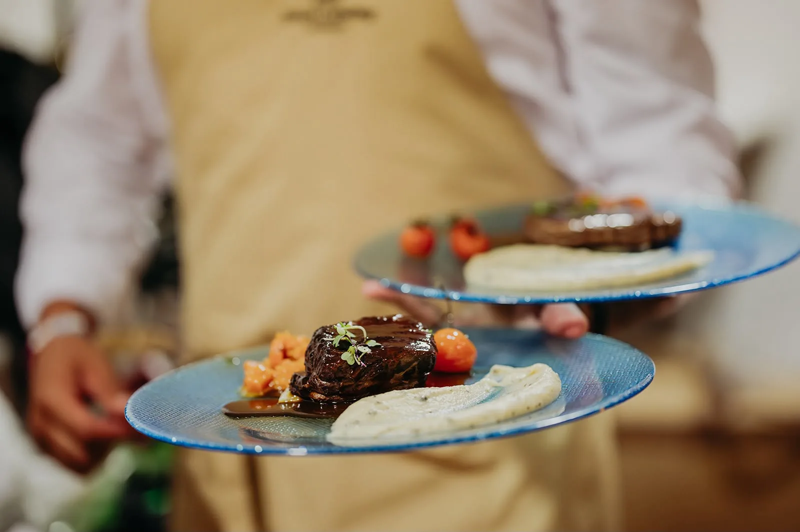 Plato principal emplatado en vajilla azul, servido en una boda