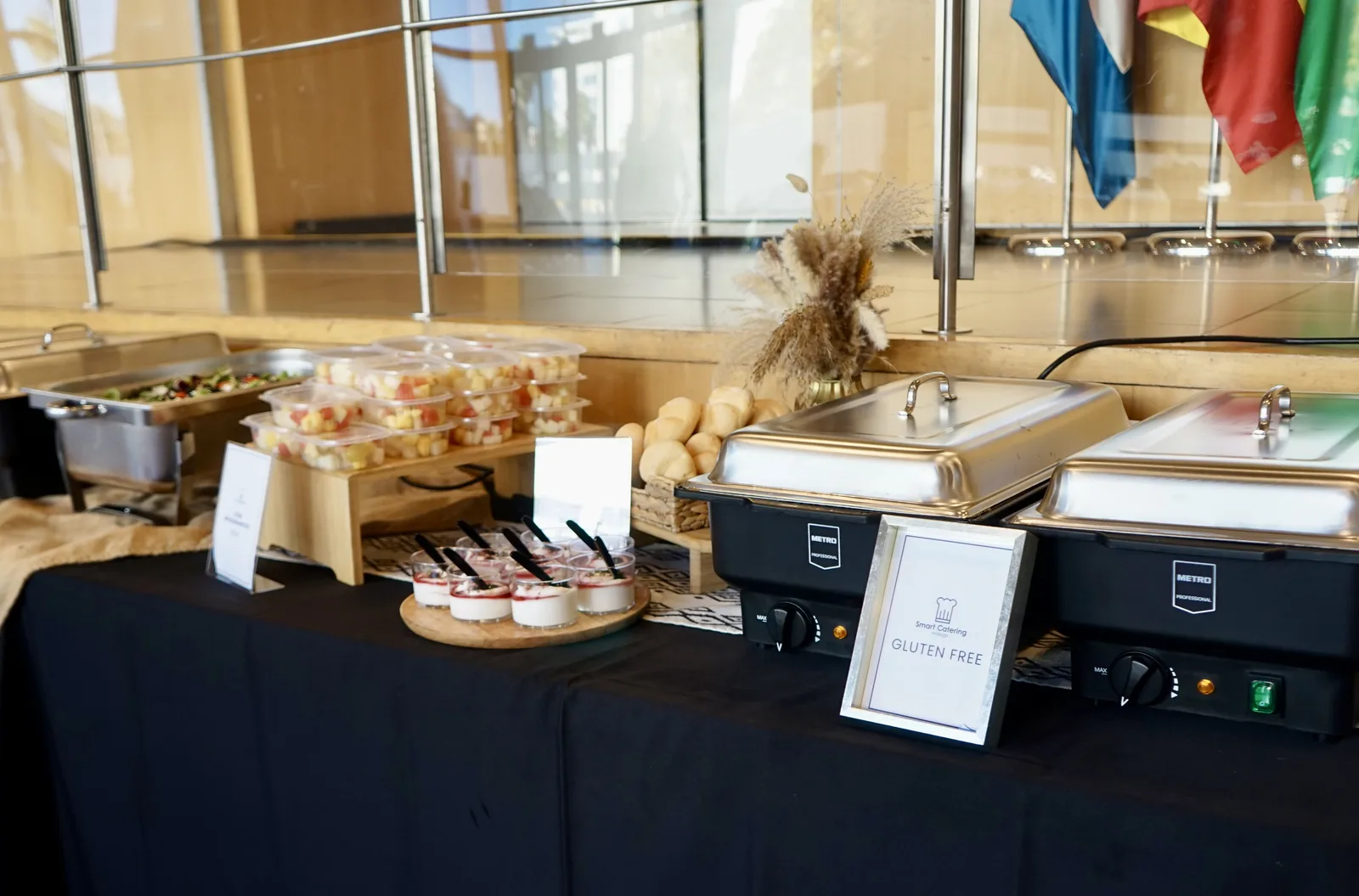 Estación gluten free con cartel oficial SmartCatering en congreso institucional, banderas de países al fondo