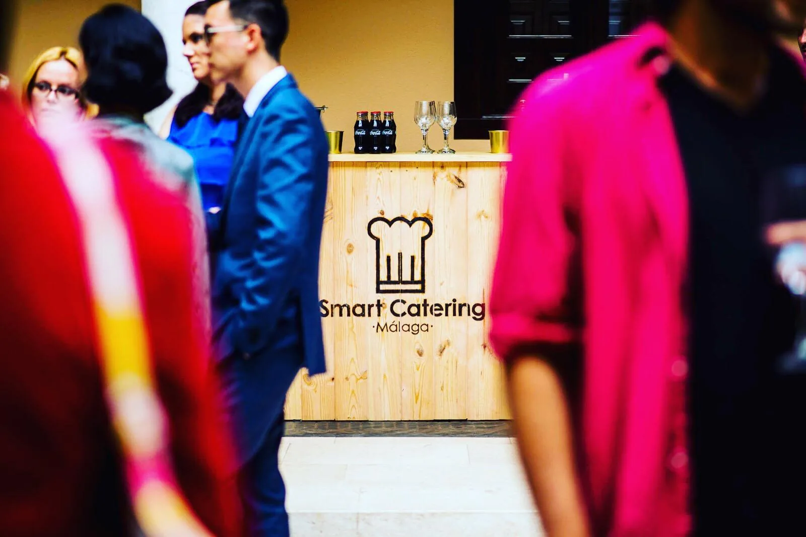 Barra de evento con logo SmartCatering y asistentes desenfocados al fondo