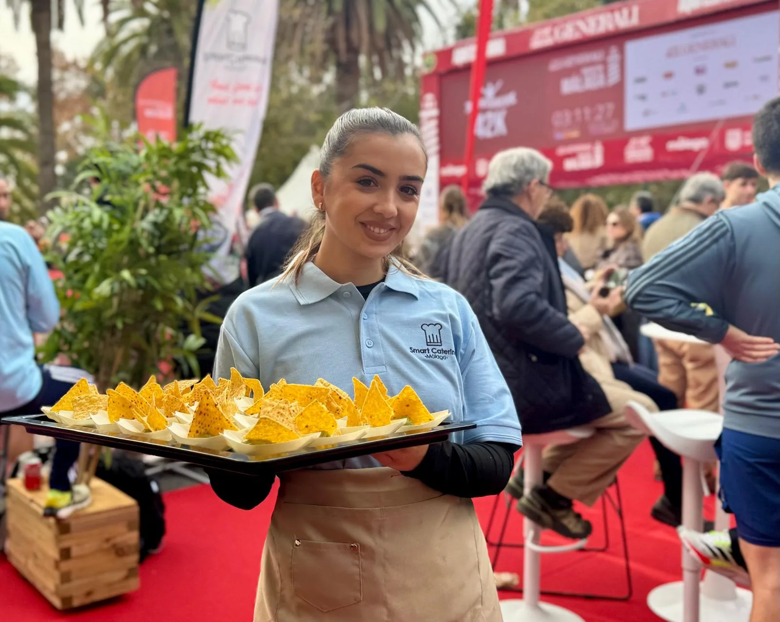 Camarera de SmartCatering Málaga con bandeja de nachos en evento deportivo patrocinado