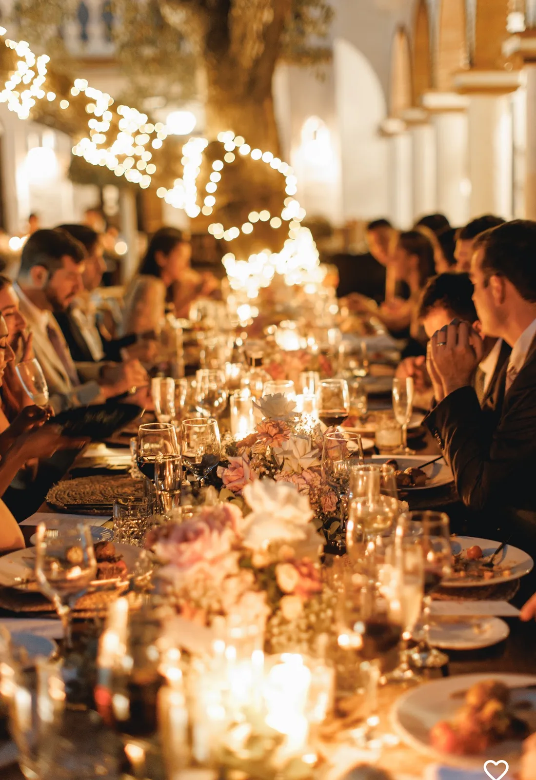 Guests dining at a long imperial table by candlelight and fairy-light strings at a destination wedding on the Costa del Sol